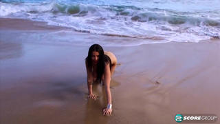 Брюнетка на пляже показывает сочную грудь